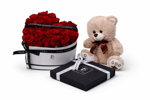 Teddy bear with a gift box and bouquet of red roses on a white background