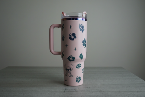 Pink tumbler with floral and geometric patterns on a gray surface