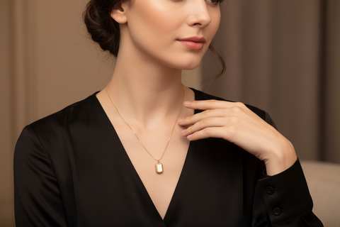 Woman wearing a gold necklace with a pendant against a neutral background